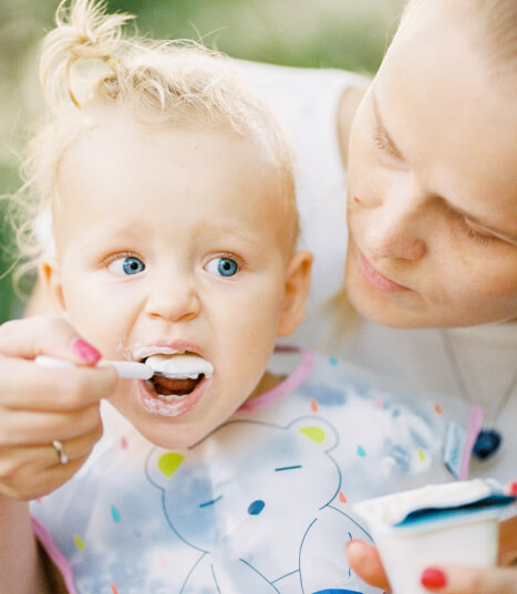 a woman feeding an ice cream to a kid