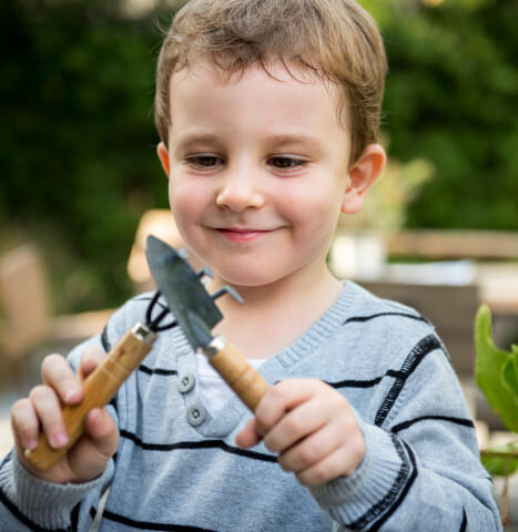 closeup shot of a little boy with garden tools